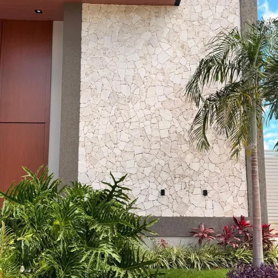 Fachada revestida em pedra com paisagismo tropical